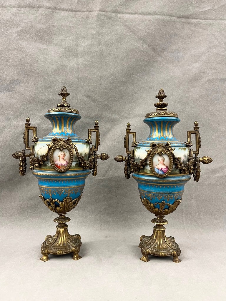 PAIR 19TH CENTURY SEVRES STYLE GILT-METAL MOUNTED PORCELAIN URNS. - H: 13 1/4 in.: PAIR 19TH CENTURY SEVRES STYLE GILT-METAL MOUNTED PORCELAIN URNS. Friezes painted with landscape decoration. Gilt metal swags center porcelain portrait medallions. - H: 13 1/4 in.