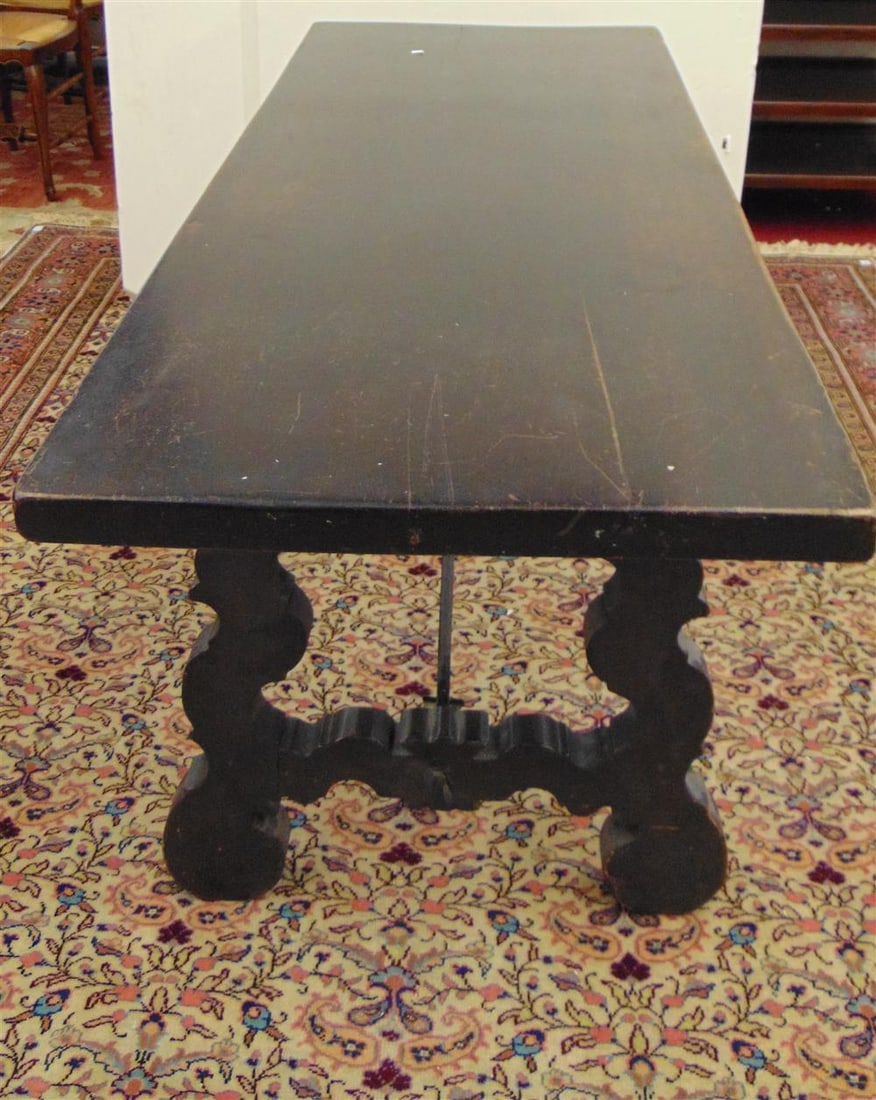 ANTIQUE SPANISH OR ITALIAN TRESTLE BASE LIBRARY TABLE, 19th century, after the 17th century. - H: 30: ANTIQUE SPANISH OR ITALIAN TRESTLE BASE LIBRARY TABLE, 19th century, after the 17th century. Deep rectangular slab top over shaped end supports joined by scrolling iron cross stretcher. - H: 30 in.; t