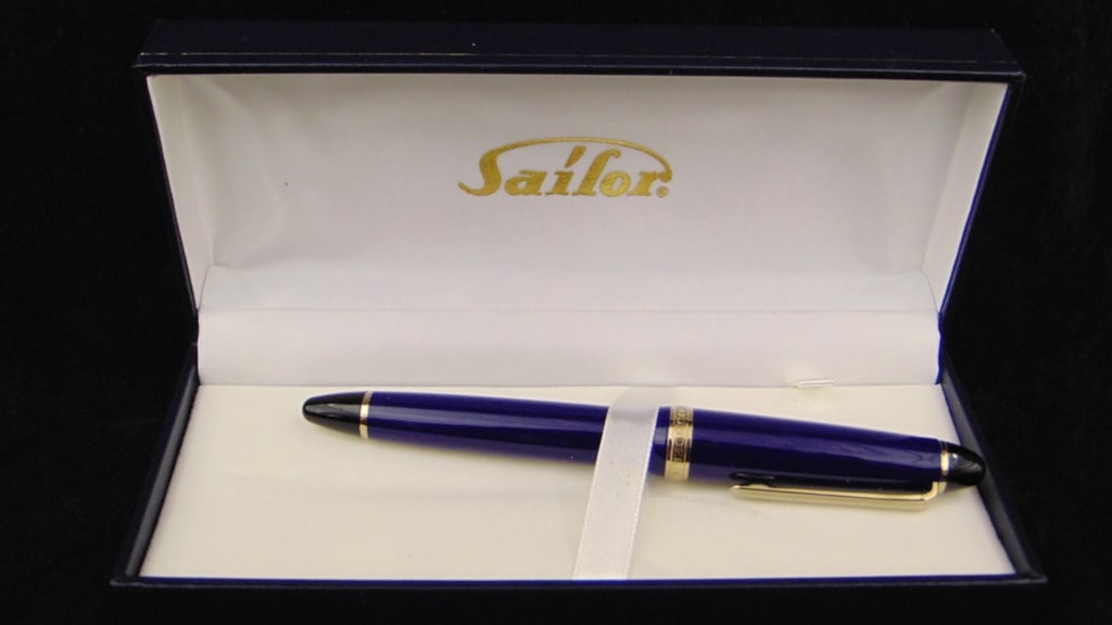 SAILOR FOUNTAIN PEN, Model 1911L.: SAILOR FOUNTAIN PEN, Model 1911L. Navy blue barrel and cap, gold-tone accents. In hinged-top box marked iwth logo, accompanied by Sailor instruction manual, polishing cloth and cartridge.