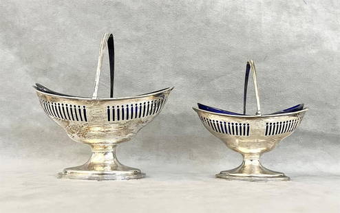 TWO GRADUATED GEORGE III NEOCLASSICAL SILVER BOAT SHAPE SUGAR BASKETS MADE BY HESTER BATEMAN,: TWO GRADUATED GEORGE III NEOCLASSICAL SILVER BOAT SHAPE SUGAR BASKETS MADE BY HESTER BATEMAN, London, 1790-91. Bail handles; pedestal bases; pierced borders; cobalt glass liners - Larger, 7 in. Wt. 10