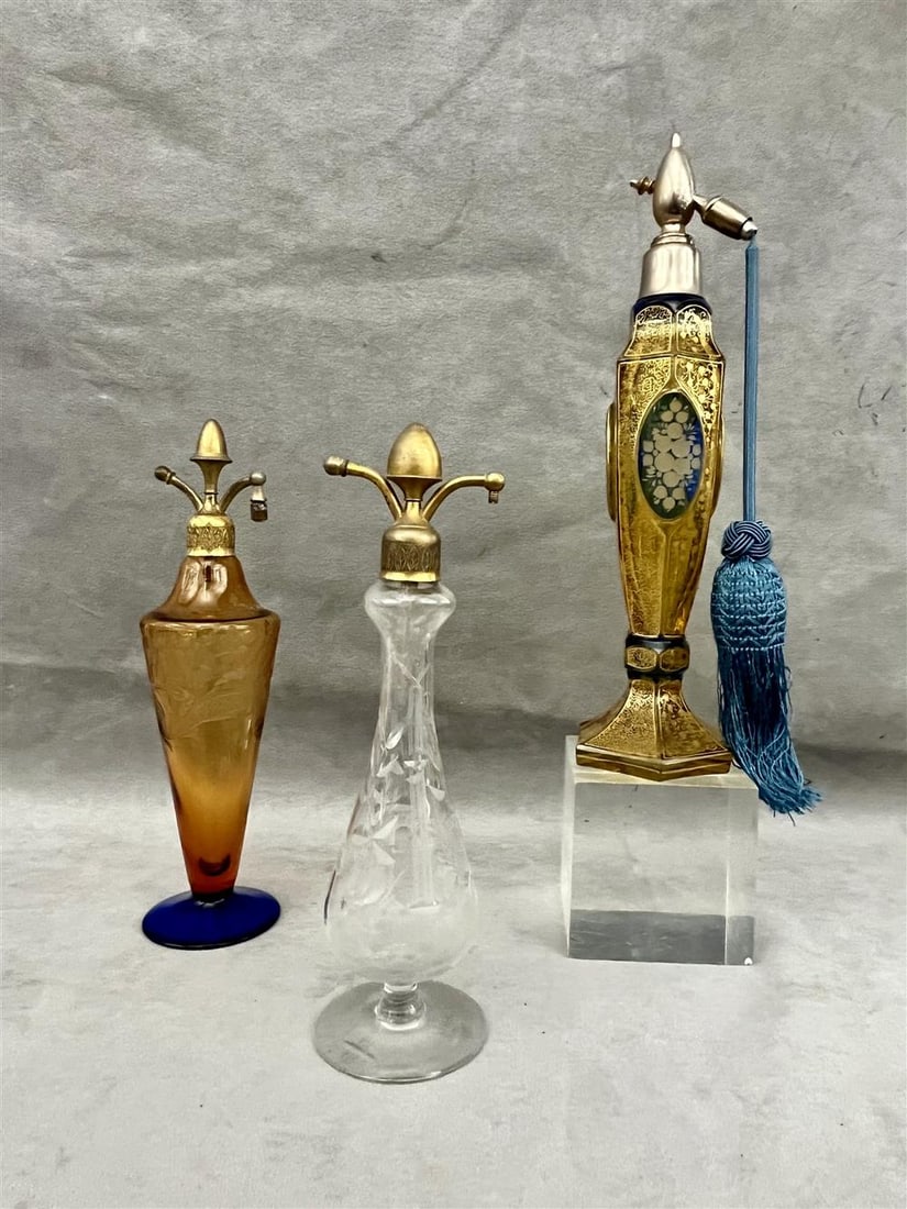 THREE VINTAGE ETCHED CRYSTAL PERFUME ATOMIZERS,: THREE VINTAGE ETCHED CRYSTAL PERFUME ATOMIZERS. One, possibly Baccarat, with raised floral etched blue glass oval reserves on pale amber ground with gilt tracery; hexagonally-paneled base )one cover c