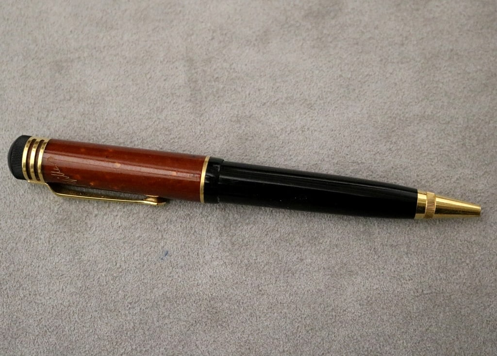 MONTBLANC BALLPOINT PEN WITH RUST-RED AND BLACK BARREL.