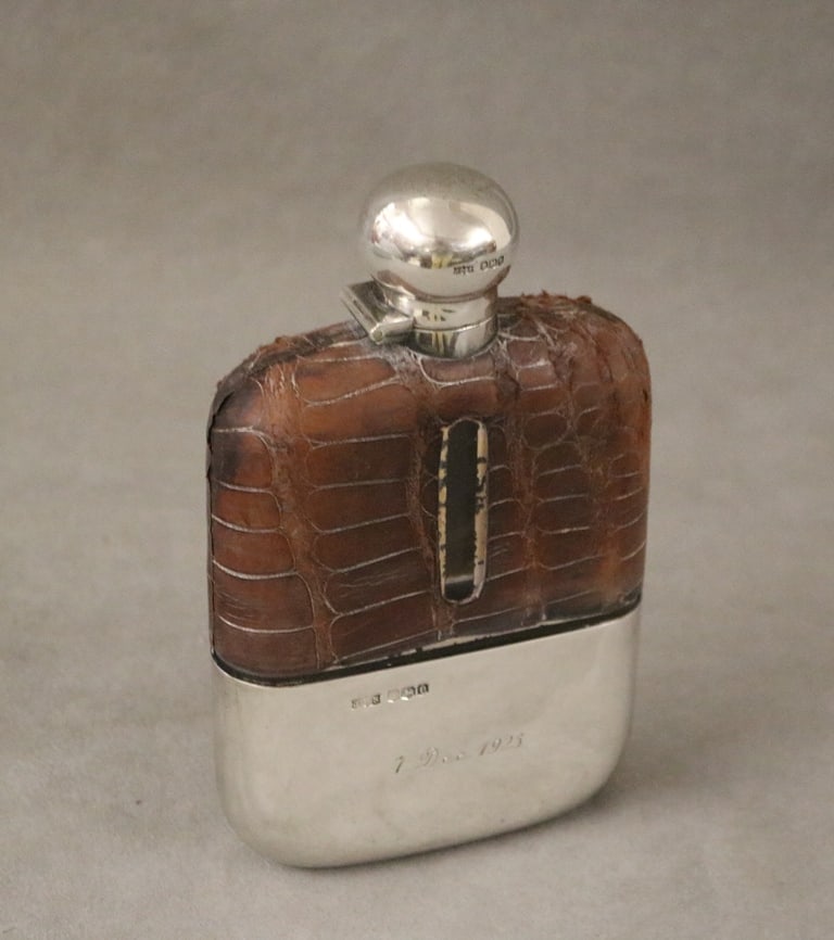 ENGLISH STERLING SILVER, BROWN ALLIGATOR AND COLORLESS GLASS HIP FLASK, early 20th century. - H: 6: ENGLISH STERLING SILVER, BROWN ALLIGATOR AND COLORLESS GLASS HIP FLASK, early 20th century. Removable sterling cup base with ornate engraved monogram - H: 6 1/4 in.