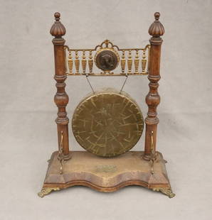 BURMESE BRASS CIRCULAR TABLE-TOP GONG IN ENGLISH BRASS-MOUNTED OAK STAND, late 19th century. - H: 20: BURMESE BRASS CIRCULAR TABLE-TOP GONG IN ENGLISH BRASS-MOUNTED OAK STAND, late 19th century. Stand has Neoclassical medallion of warrior, and brass plaque dated 1898 - H: 20 in. W: 15 1/2 in.