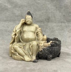 CHINESE GRAY-BEIGE-TO-CHARCOAL COLOR SOAPSTONE BRUSHWASHER CARVED AS SEATED LOHAN FIGURE. - H: 6 in.