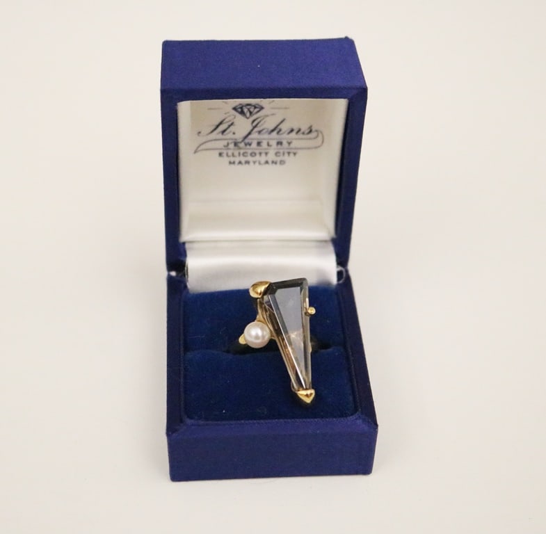 10K YELLOW GOLD, CULTURED PEARL AND SMOKY QUARTZ CONTEMPORARY DESIGN RING.: 10K YELLOW GOLD, CULTURED PEARL AND SMOKY QUARTZ CONTEMPORARY DESIGN RING. Narrow triangular smoky quartz raised in three prongs with off-set cultured pearl. Ring size: 6 1/2. Gross wt: 4 dwt.