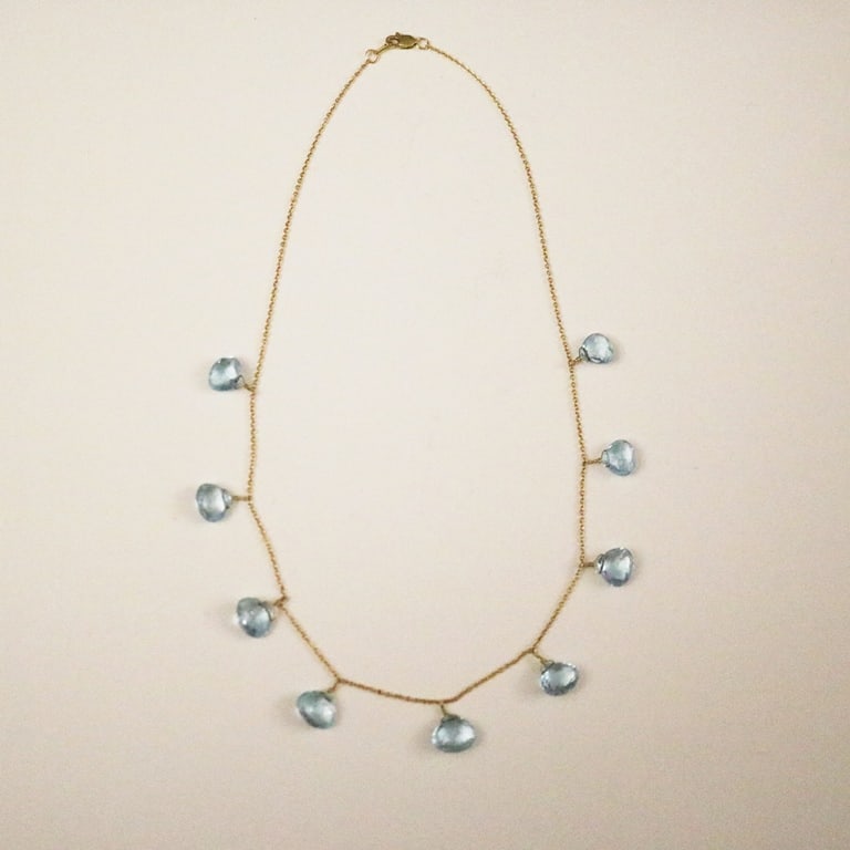 18K (750) YELLOW GOLD AND AQUAMARINE DELICATE FRINGE STYLE FLEXIBLE CHAIN CHOKER. - L: 16".: 18K (750) YELLOW GOLD AND AQUAMARINE DELICATE FRINGE STYLE FLEXIBLE CHAIN CHOKER. Oval-link chain with lobster claw clasp, spaced with nine matched briolette-cut aquamarine drops. - L: 16".