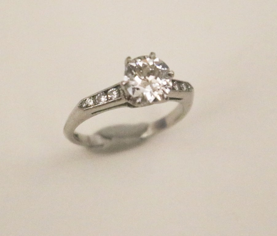 PLATINUM (10% IRIDIUM) AND DIAMOND ENGAGEMENT TYPE RING.: PLATINUM (10% IRIDIUM) AND DIAMOND ENGAGEMENT TYPE RING. Transitional brilliant-cut round diamond weighing approx. 1.50 ct. raised by six prongs; shoulders of shank each set with three graduated brill
