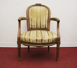 LOUIS XVI CARVED AND UPHOLSTERED FRUITWOOD FAUTEUIL. Domed back carved with ribbon and bow-knot