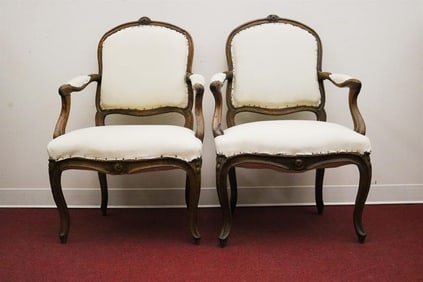 PAIR LOUIS XV CARVED OAK UPHOLSTERED FAUTEUILS. Crests carved with floral medallions; molded frames;
