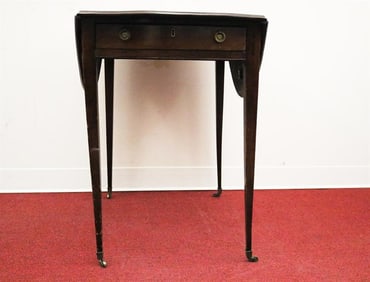 GEORGE III MAHOGANY OVAL-TOP PEMBROKE TABLE. Drawer fitted with brass ring pulls; on casters.
