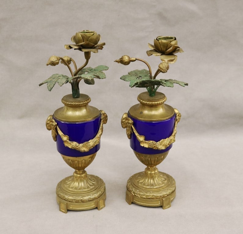 PAIR NEOCLASICAL BRONZE AND COBALT GLASS TABLE-TOP ONE LIGHT CANDLESTICKS, 19th century. - H: 10 1/4: PAIR NEOCLASICAL BRONZE AND COBALT GLASS TABLE-TOP ONE LIGHT CANDLESTICKS, 19th century. Cast as urns issuing rose blossom nozzle with green-painted leaves. - H: 10 1/4 in.