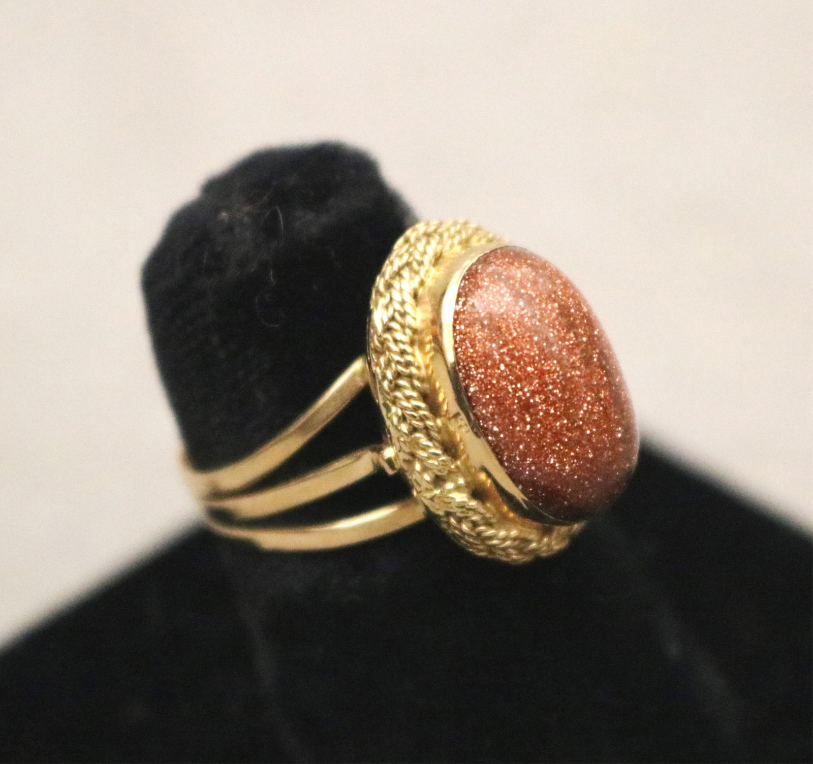 EGYPTIAN YELLOW GOLD AND OVAL GOLDSTONE CABOCHON RING IN OVAL SETTING WITH BRAIDED BORDER (1 of 11)