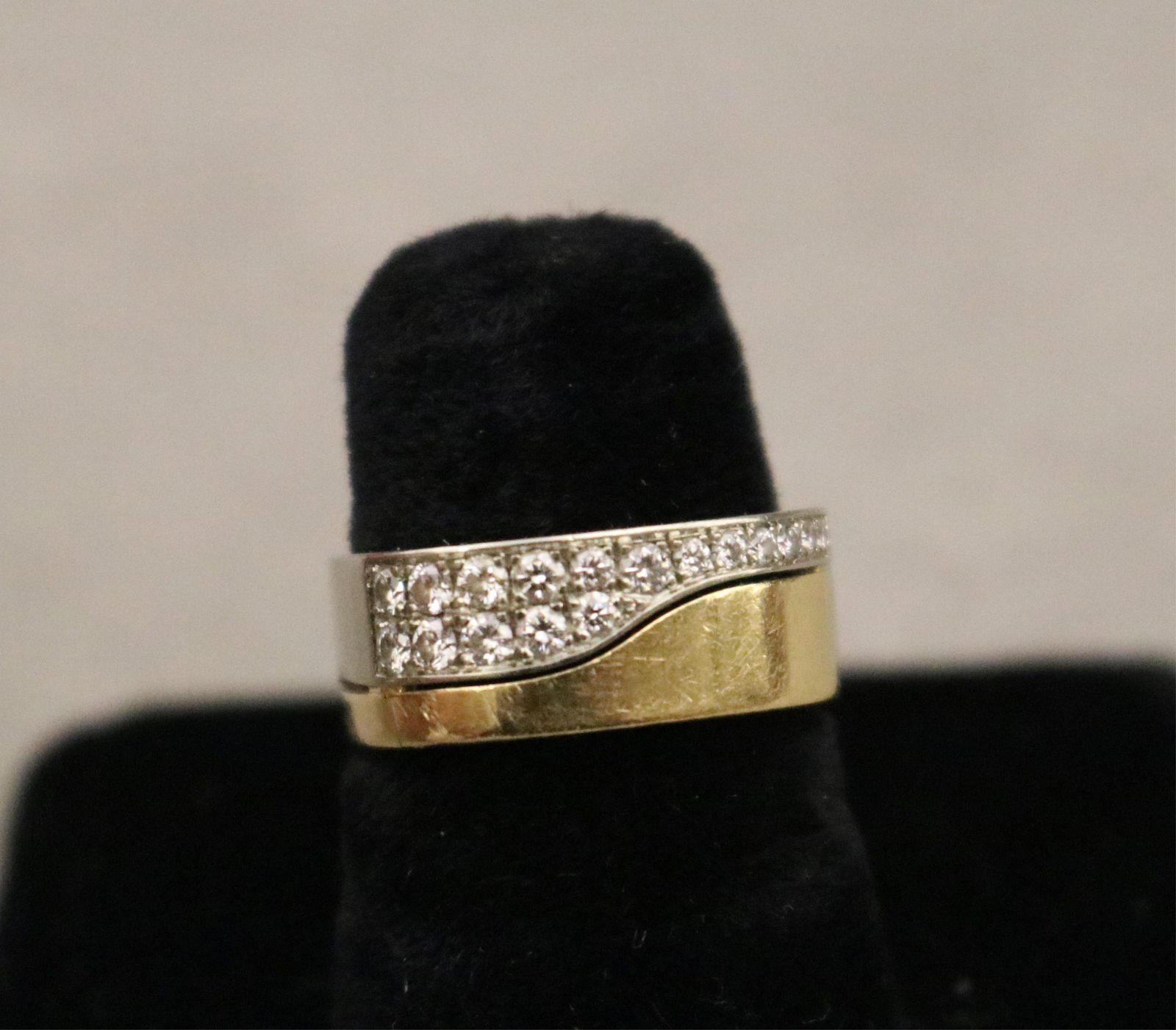 18K YELLOW AND WHITE GOLD CONTEMPORARY DESIGN BAND Ring size: 5. Gross wt. 4 dwt.: 18K YELLOW AND WHITE GOLD CONTEMPORARY DESIGN BANDCushion-shape band with yellow and white gold fitted asymetrical sections, the white gold portion pave-set with 17 graduated brilliant-cut round diamo