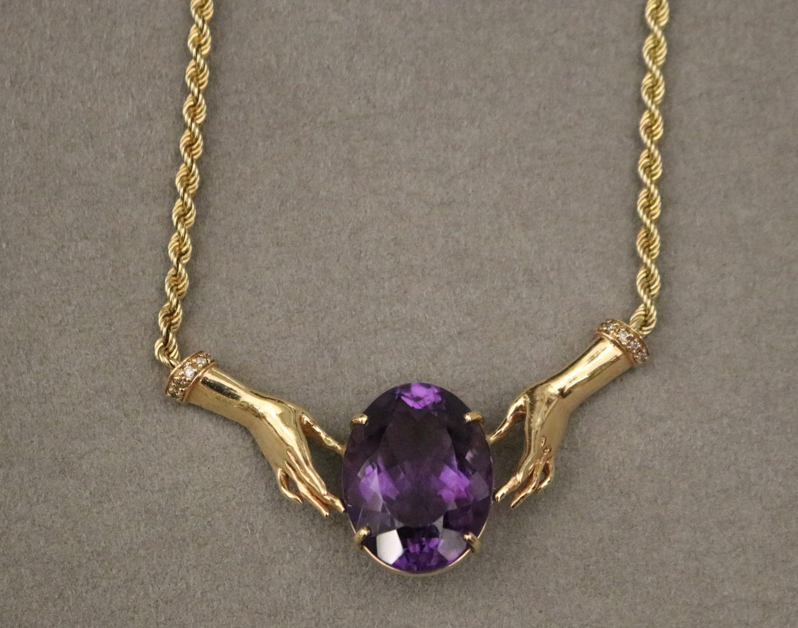 14K YELLOW GOLD, DIAMOND AND AMETHYST FLEXIBLE ROPE CHAIN CHOKER: 14K YELLOW GOLD, DIAMOND AND AMETHYST FLEXIBLE ROPE CHAIN CHOKERRope with throat ornament constructed of oval amethyst weighing app. 15 ct. centered by pair of hands wearing bracelets each set with si