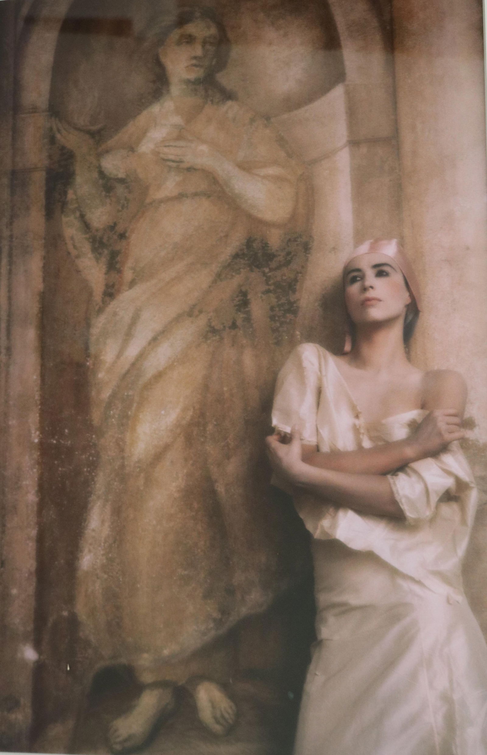 Joyce Tenneson, American Born 1945, Portrait of Suzanne in Front of a Mural, Size (as matted): 19.5: JOYCE TENNESONAmerican, Born 1945Portrait of Suzanne in Front of a MuralColor photograph. Joyce Tenneson is likely using ther frequent collaborator Suzanne who is dressed in a white, silk-like garment