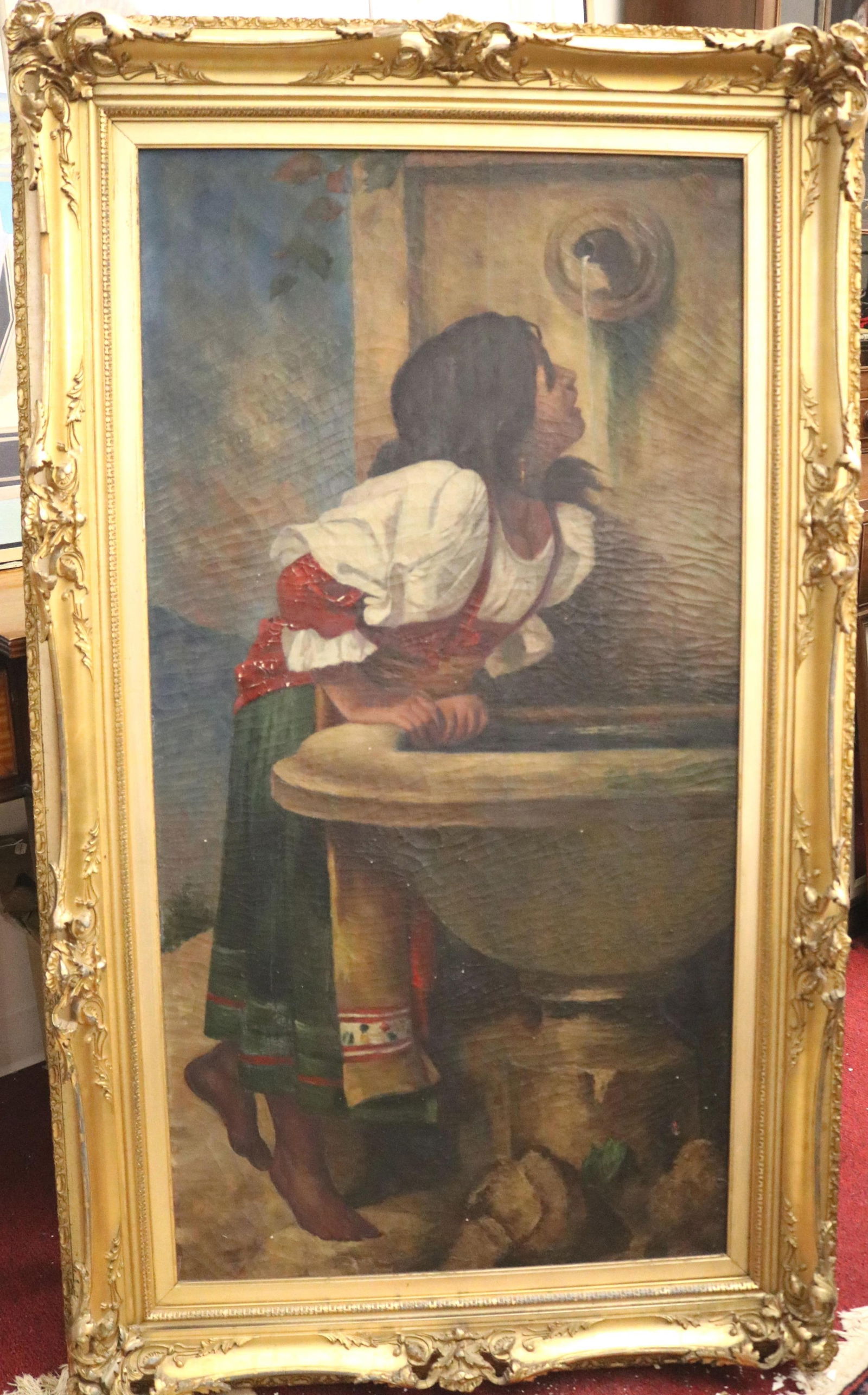 Italian School , 19th Century, At the Fountain, Oil on canvas, Artwork: 24 x 48 inches (excluding: ITALIAN SCHOOL19th CenturyAt the FountainOil on canvas(for restoration) Framed painting depicts a young woman leaning over a large, stone basin to drink from a flowing fountain. Framed in an ornate fr