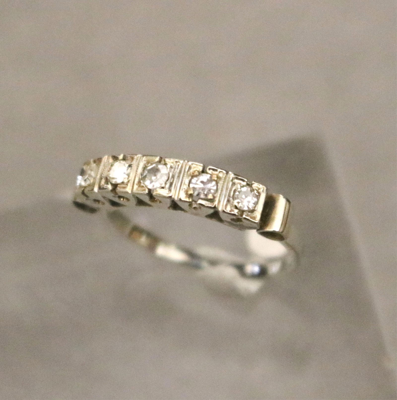 WHITE GOLD AND DIAMOND BAND - Ring size 5. Gross wt. 1 dwt..: WHITE GOLD AND DIAMOND BAND Row of five matched single-cut round diamonds together weighing app. .25 ct., each held in box setting. Ring size 5. Gross wt. 1 dwt.