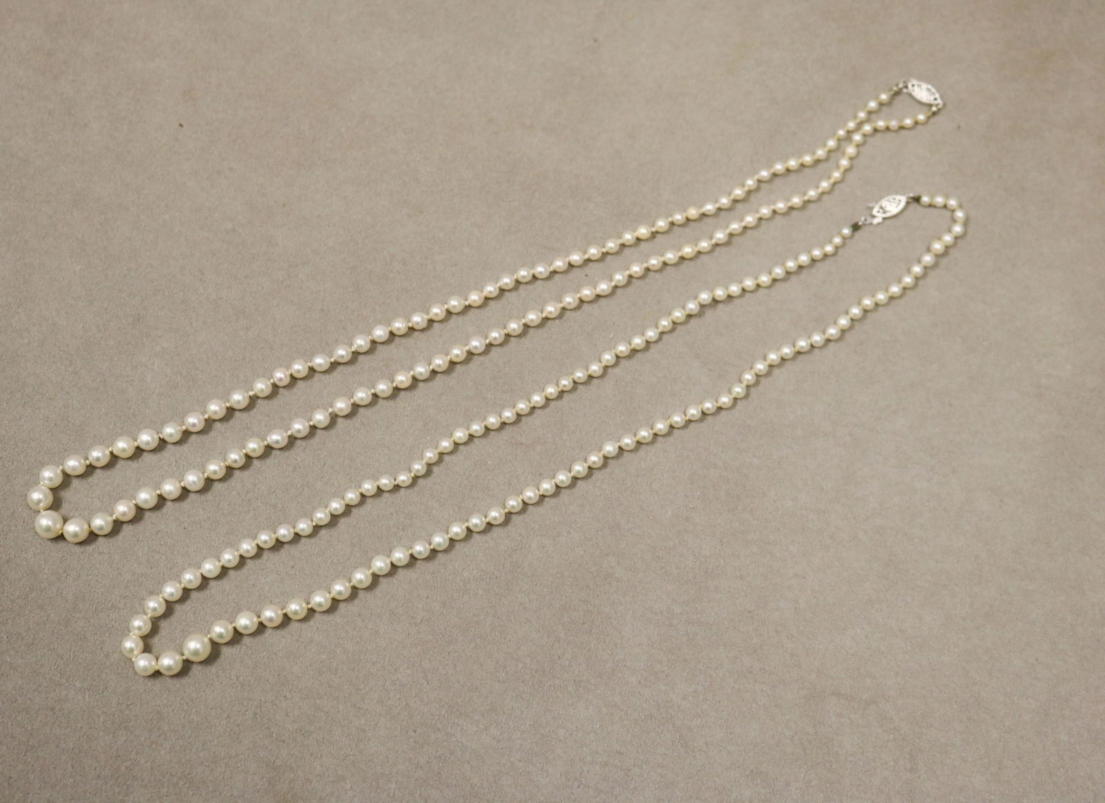 TWO GRADUATED WHITE CULTURED PEARL NECKLACES WITH WHITE GOLD FILIGREE NAVETTE-SHAPE CLASPS - .: TWO GRADUATED WHITE CULTURED PEARL NECKLACES WITH WHITE GOLD FILIGREE NAVETTE-SHAPE CLASPS Pearls graduate from 3 to 7mm. One, L: 20 in., with 10K clasp. Other, L: 21 in. with 14K clasp
