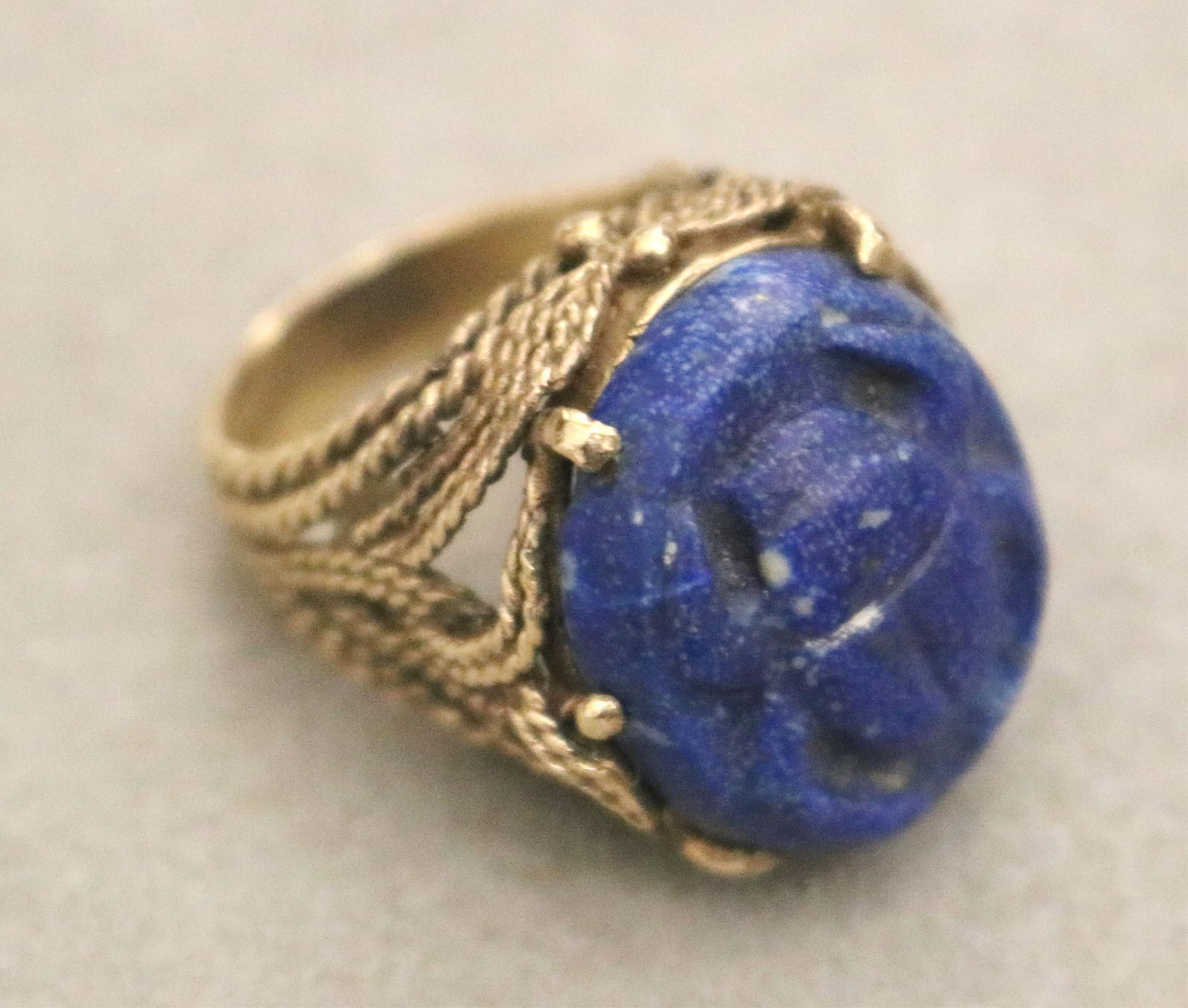 14K YELLOW GOLD AND CARVED SODALITE SCARAB DESIGN RING - Ring size: 6. Gross wt. 8 dwt..: 14K YELLOW GOLD AND CARVED SODALITE SCARAB DESIGN RING Oval sodalite panel carved in relief with scarab motif held by six prongs in openwork rope-design setting. Ring size: 6. Gross wt. 8 dwt.