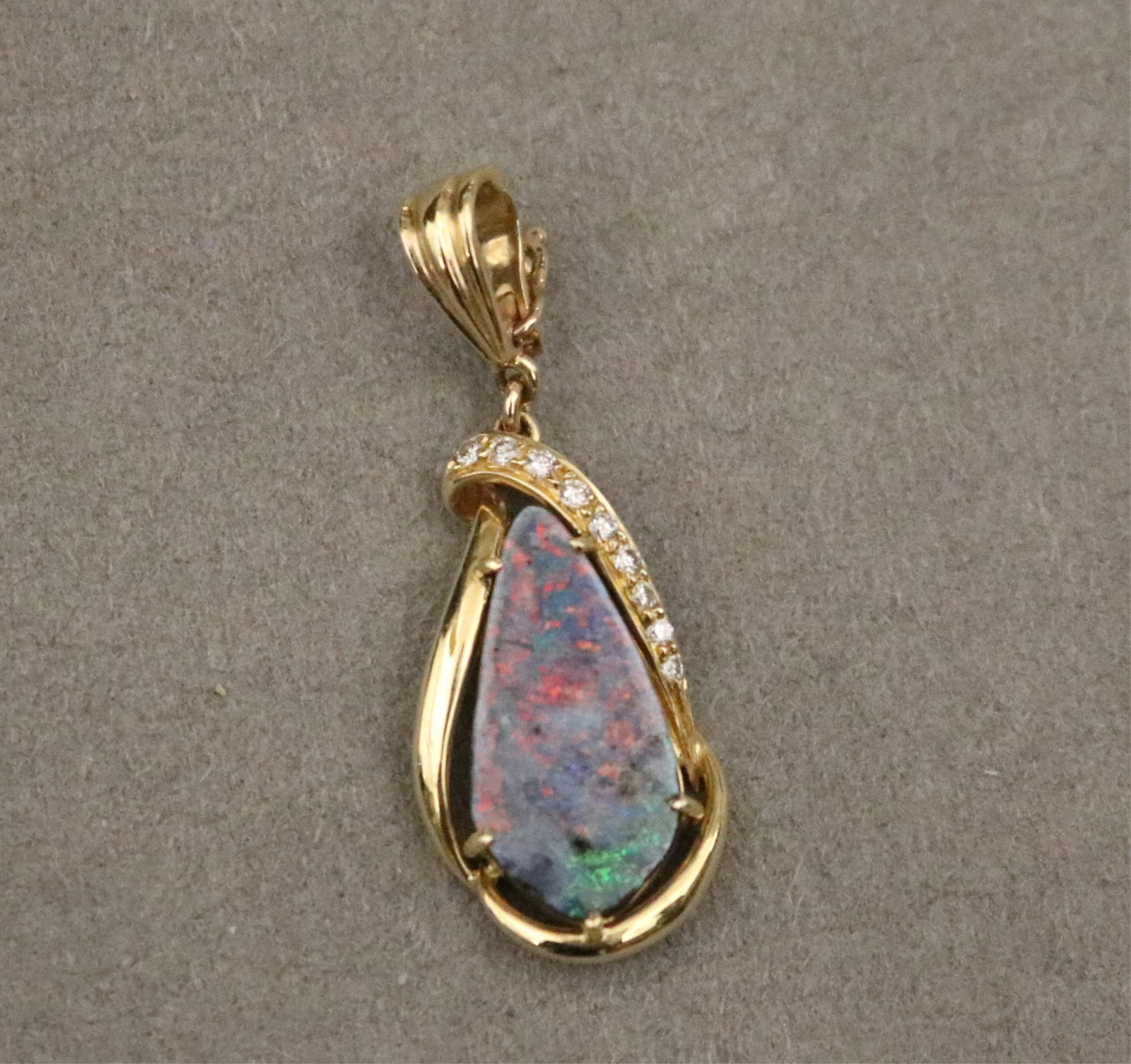 14K YELLOW GOLD, DIAMOND AND BLACK BOULDER OPAL PENDANT - L: 1 3/8 in., including hinged bail..: 14K YELLOW GOLD, DIAMOND AND BLACK BOULDER OPAL PENDANT Pear-shape opal weighing 4.12 ct. centered in looped drop setting with nine brilliant-cut diamonds. L: 1 3/8 in., including hinged bail.