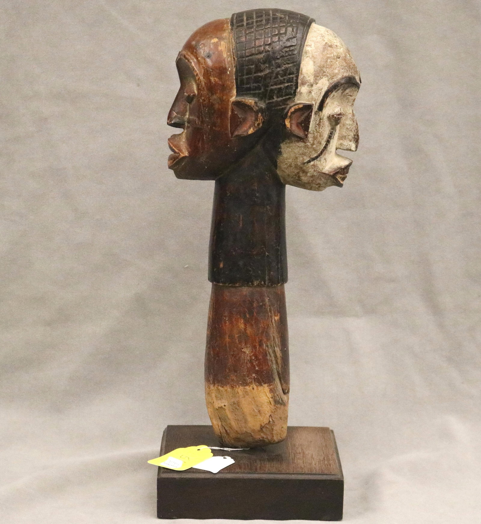 NIGERIAN IBGO JANUS RITUAL SCEPTER - Height: 19 inches (including base).: NIGERIAN IBGO JANUS RITUAL SCEPTER This patinated Igbo Janus scepter from Nigeria is a striking ritual object characterized by its dual-faced (Janus) head, symbolizing the ability to see into both the