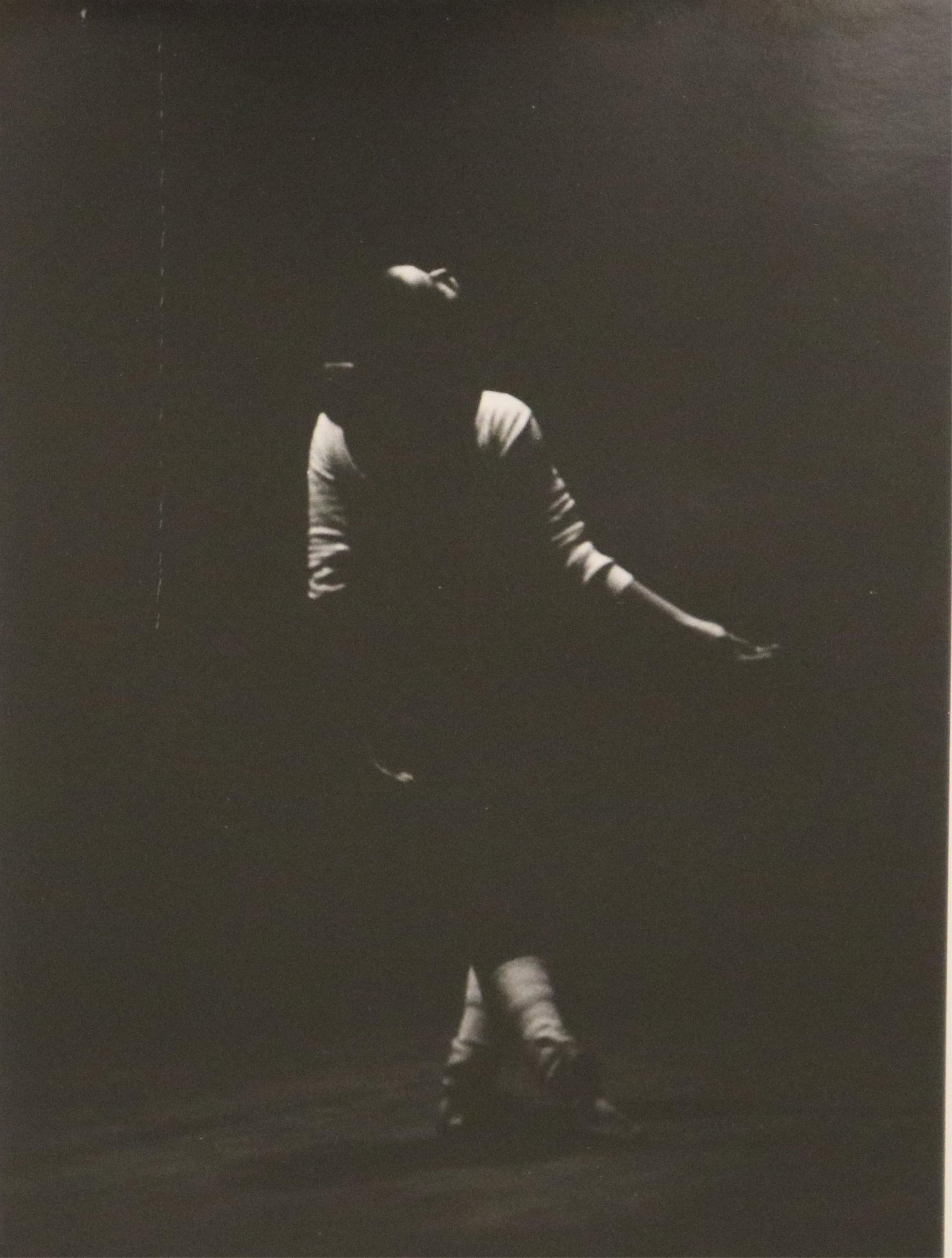 CONTEMPORARY AMERICAN ARTIST , (20th century). Solitary Dancer against a Dark, Minimalist: CONTEMPORARY AMERICAN ARTIST20th centurySolitary Dancer against a Dark, Minimalist BackgroundphotographThis black-and-white photograph features a solitary figure, likely a dancer, set against a dark a