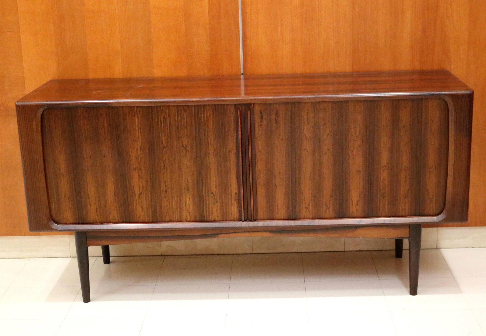 MID-CENTURY MODERN ROSEWOOD SIDEBOARD/CREDENZA - H: 31 1/2". W: 65". D: 19 3/4"..: MID-CENTURY MODERN ROSEWOOD SIDEBOARD/CREDENZA Pair tamboured sliding doors open to three narrow shelves and open compartment. H: 31 1/2". W: 65". D: 19 3/4".