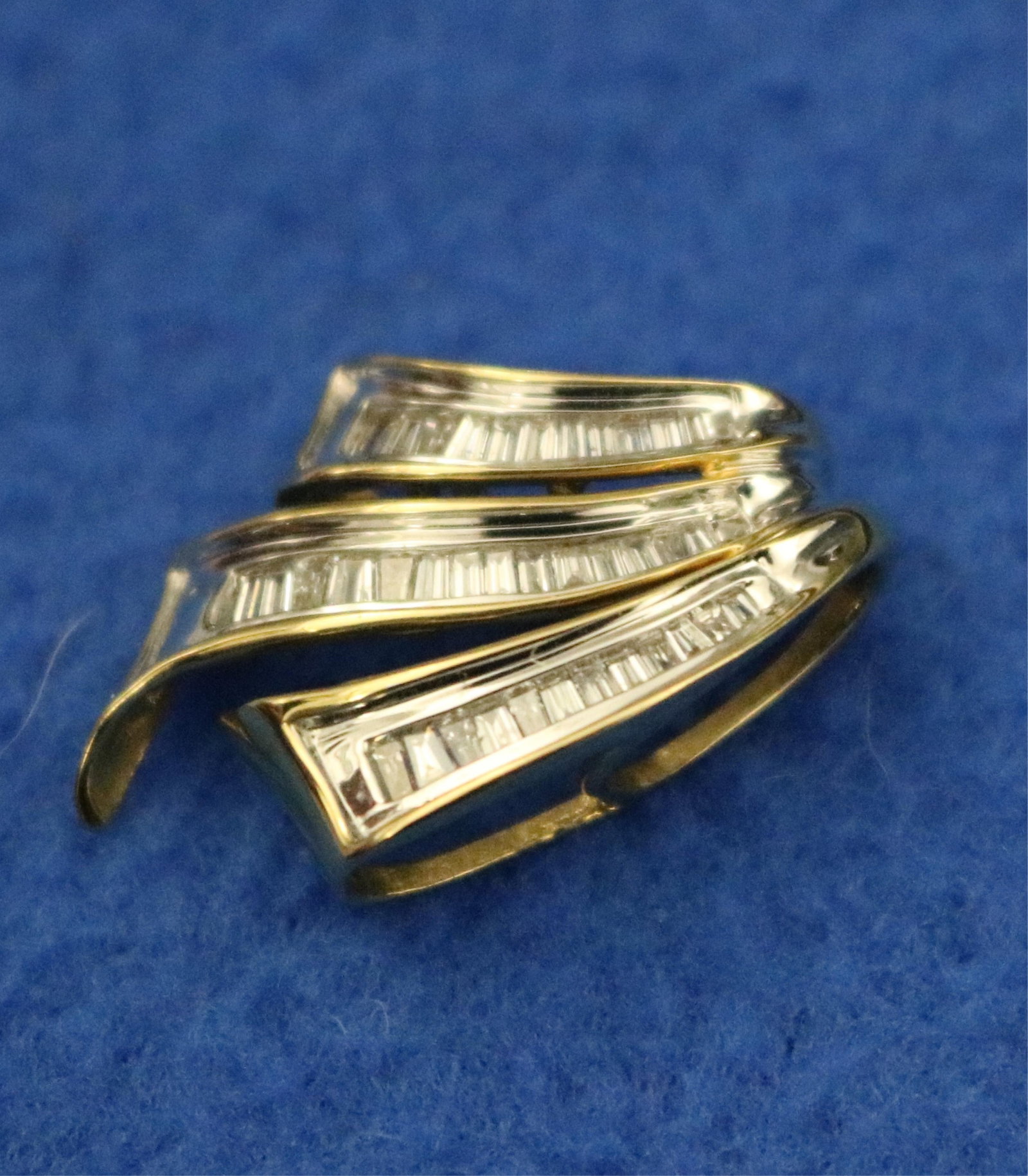 14K BRIGHT-POLISHED YELLOW AND WHITE GOLD AND DIAMOND PENDANT/ NECKLACE ENHANCER - L: 1 in. Gross: 14K BRIGHT-POLISHED YELLOW AND WHITE GOLD AND DIAMOND PENDANT/ NECKLACE ENHANCER Three scrolling ribbons set with total of 37 graduated, tapering baguette diamonds together weighing app. 1.00 ct. L: 1