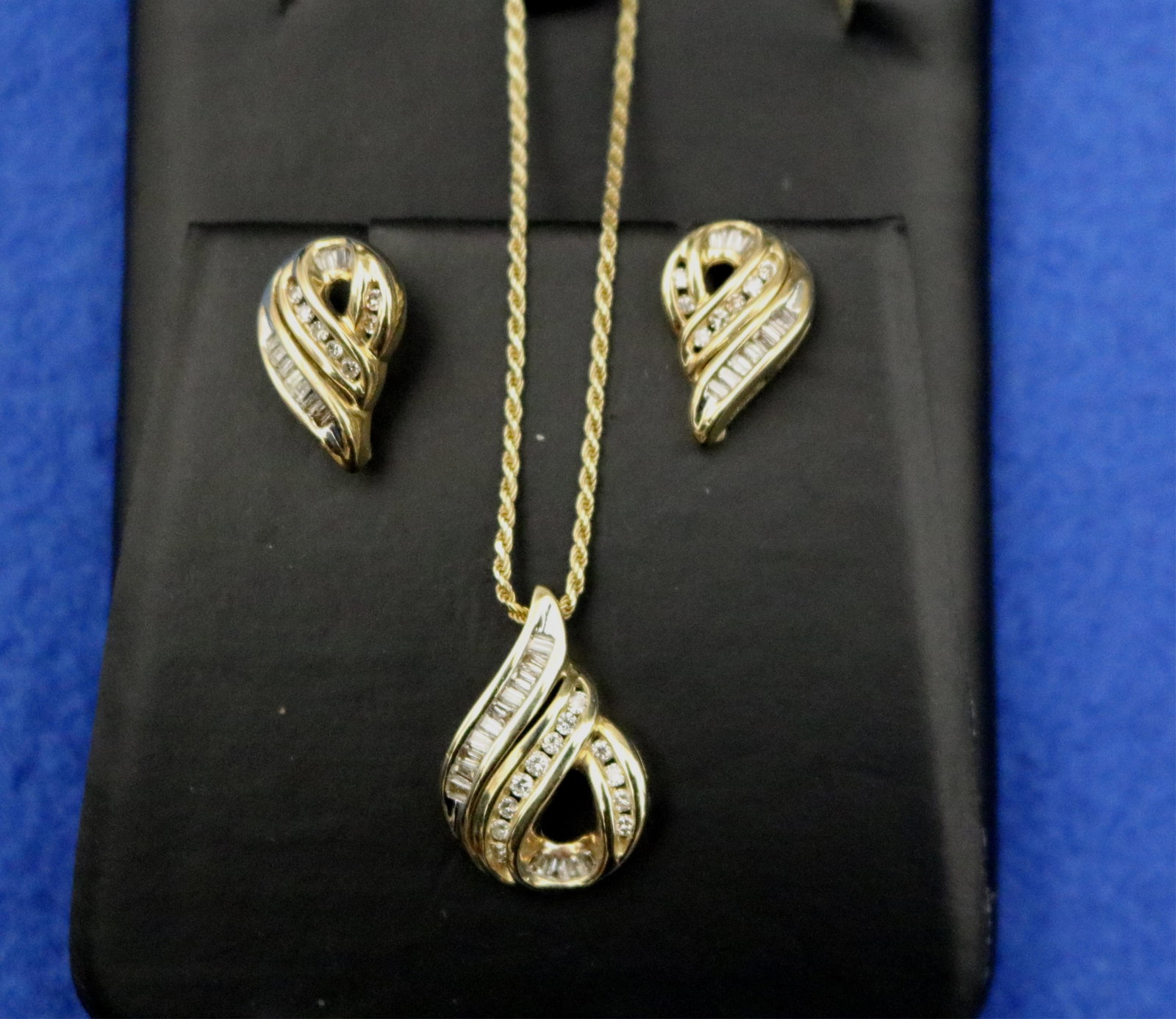ITALIAN 14K YELLOW AND WHITE GOLD AND DIAMOND PENDANT ON 14K FLEXIBLE ROPE CHAIN, WITH PAIR MATCHING: ITALIAN 14K YELLOW AND WHITE GOLD AND DIAMOND PENDANT ON 14K FLEXIBLE ROPE CHAIN, WITH PAIR MATCHING SCREW-BACK EARRINGS Scrolling loop pendant set with 14 tapering baguette diamonds and eight brillia