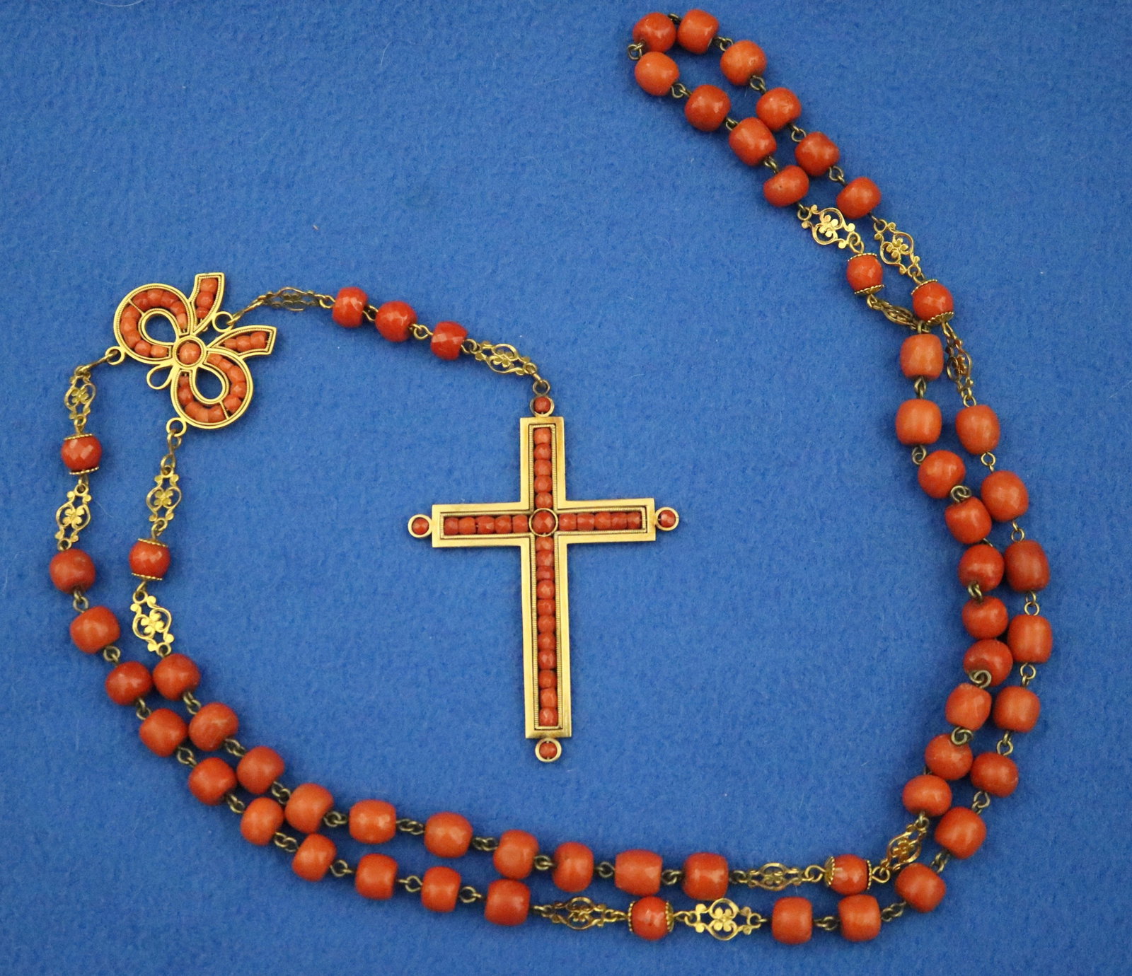 18K YELLOW GOLD AND ORANGE CORAL BEAD ROSARY. - L: 26", suspended length, including cross.,.: 18K YELLOW GOLD AND ORANGE CORAL BEAD ROSARY. Gold cross centering intersecting lines of matched faceted coral beads. Suspended on chain of facted and smooth-polished coral beads measuring 8.5-9mm,