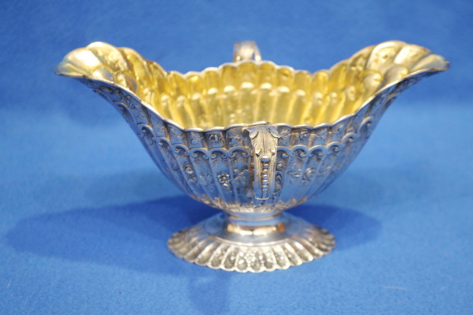 GERMAN STERLING SILVER GRAVY BOAT 19th century - H: 4 1/2 in. L: 8 1/4 in. Wt. 12.5 troy oz..: GERMAN STERLING SILVER GRAVY BOAT 19th century Shaped and fluted, two-handle boat-form with relief-floral decoration; vermeil interior; hallmarked. H: 4 1/2 in. L: 8 1/4 in. Wt. 12.5 troy oz.