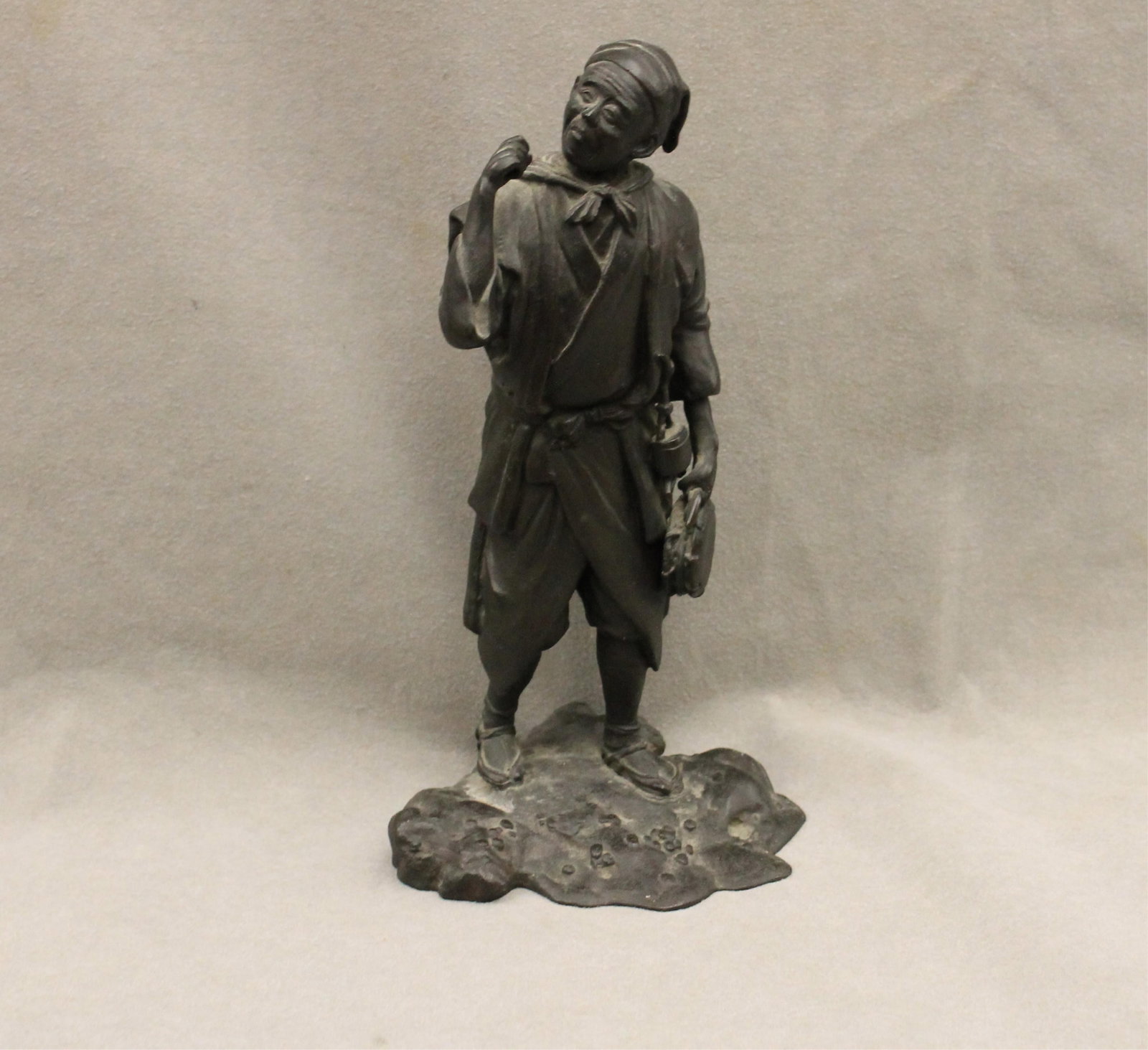 JAPANESE BRONZE FIGURE CAST AS STANDING PEASANT WORKER ON NATURALISTIC ROCKY GROUND 19th century -: JAPANESE BRONZE FIGURE CAST AS STANDING PEASANT WORKER ON NATURALISTIC ROCKY GROUND 19th century Character foundry mark at base H: 9 1/2 in.