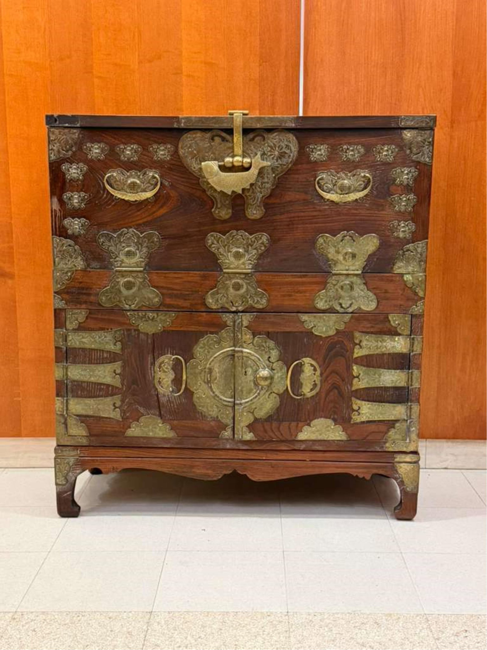 KOREAN BRASS-MOUNTED ELMWOOD TANSU - H: 44 in. D: 16 1/2 in..: KOREAN BRASS-MOUNTED ELMWOOD TANSU Drop-front panel over pair cabinet doors; elaborate butterfly mounts, latch and hinges; fish-form lock; bailside handles; dovetailed construction H: 44 in. D: 16