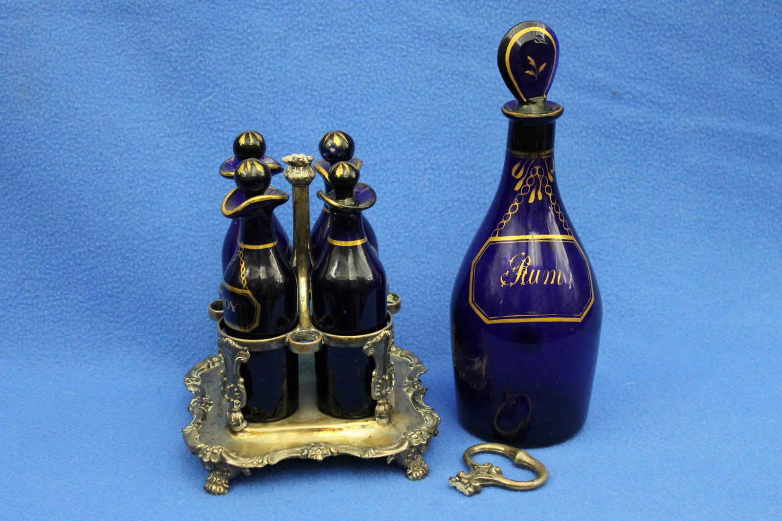 FOUR ENGLISH GILT-DECORATED AND COBALT GLASS SAUCE BOTTLES AND ONE LARGER MATCHING RUM BOTTLE early (1 of 5)