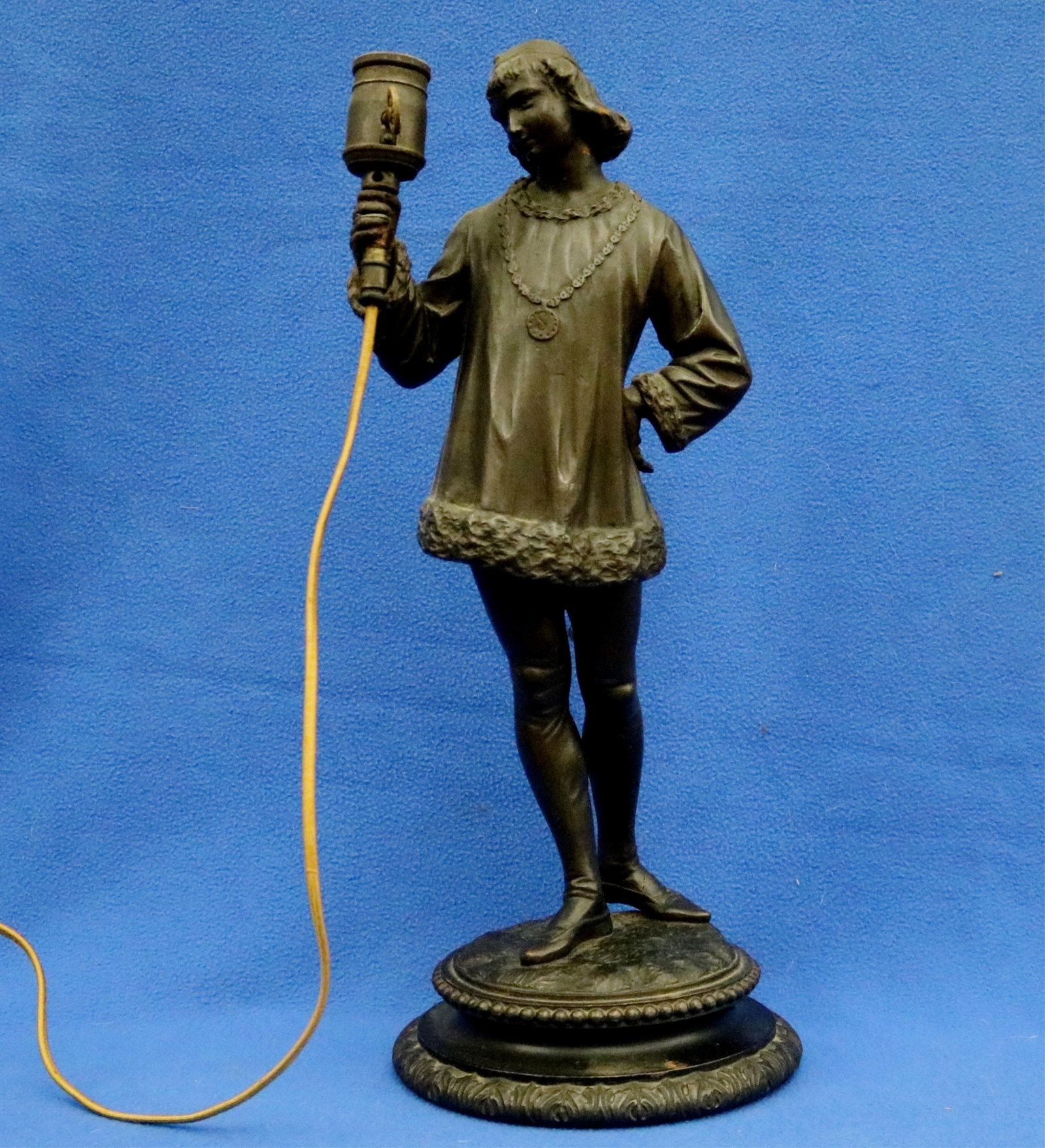 WOODEN SCULPTURE OF NOBLE FIGURE OR PAGE IN MEDIEVAL-STYLE ATTIRE MOUNTED AS TABLE LAMP 19th century: WOODEN SCULPTURE OF NOBLE FIGURE OR PAGE IN MEDIEVAL-STYLE ATTIRE MOUNTED AS TABLE LAMP 19th century Ornate tiered base with beaded and foliate decorative bands. H: 19 in.
