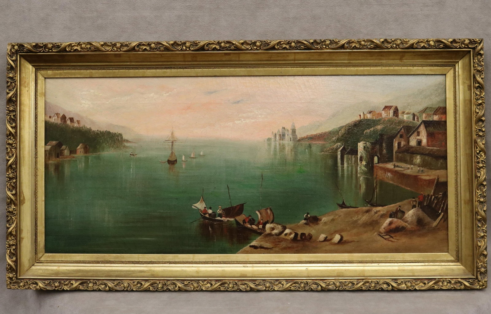 ITALIAN SCHOOL (19th century). Lakeside Vesper, Oil on canvas, 12 x 27 inches; frame: 16 x 31 inches: ITALIAN SCHOOL 19th century Lakeside Vesper Oil on canvas Unsigned panoramic Italian landscape painting of a serene coastal or lakeside town, where rustic stone buildings and a distant cathedral are m