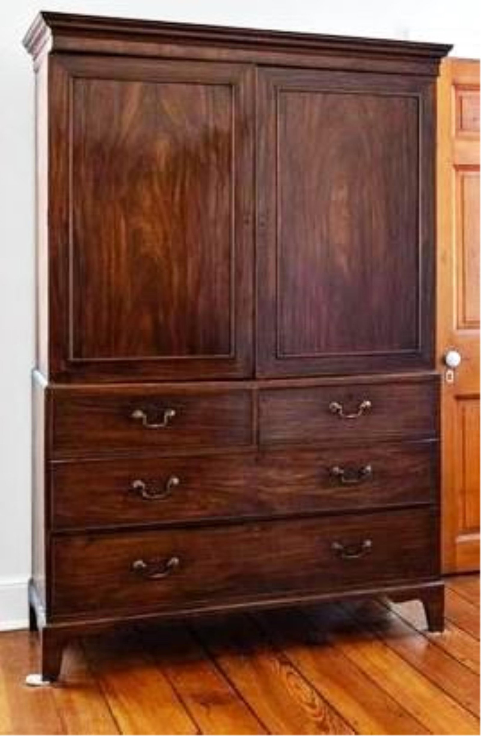 GEORGE III MAHOGANY LINEN PRESS In two parts - H: 81 in. W: 51 1/4 in. D: 23 1/2 in..: GEORGE III MAHOGANY LINEN PRESS In two parts Flat, molded cornice over frieze panel above pair paneled cabinet doors; lower section has three graduated full-width drawers, all cock-beaded; straight br