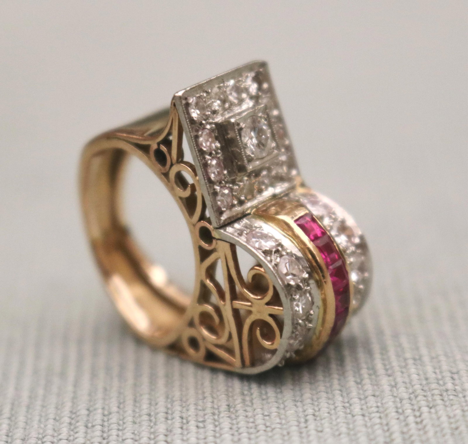 1940s 14K YELLOW AND WHITE GOLD DIAMOND AND RUBY GEOMETRIC-DESIGN RETRO RING - Ring size: 2 1/4 .: 1940s 14K YELLOW AND WHITE GOLD DIAMOND AND RUBY GEOMETRIC-DESIGN RETRO RING Square of 13 brilliant-cut and single-cut round diamonds sided by arch of ten additional round diamonds centering channel o