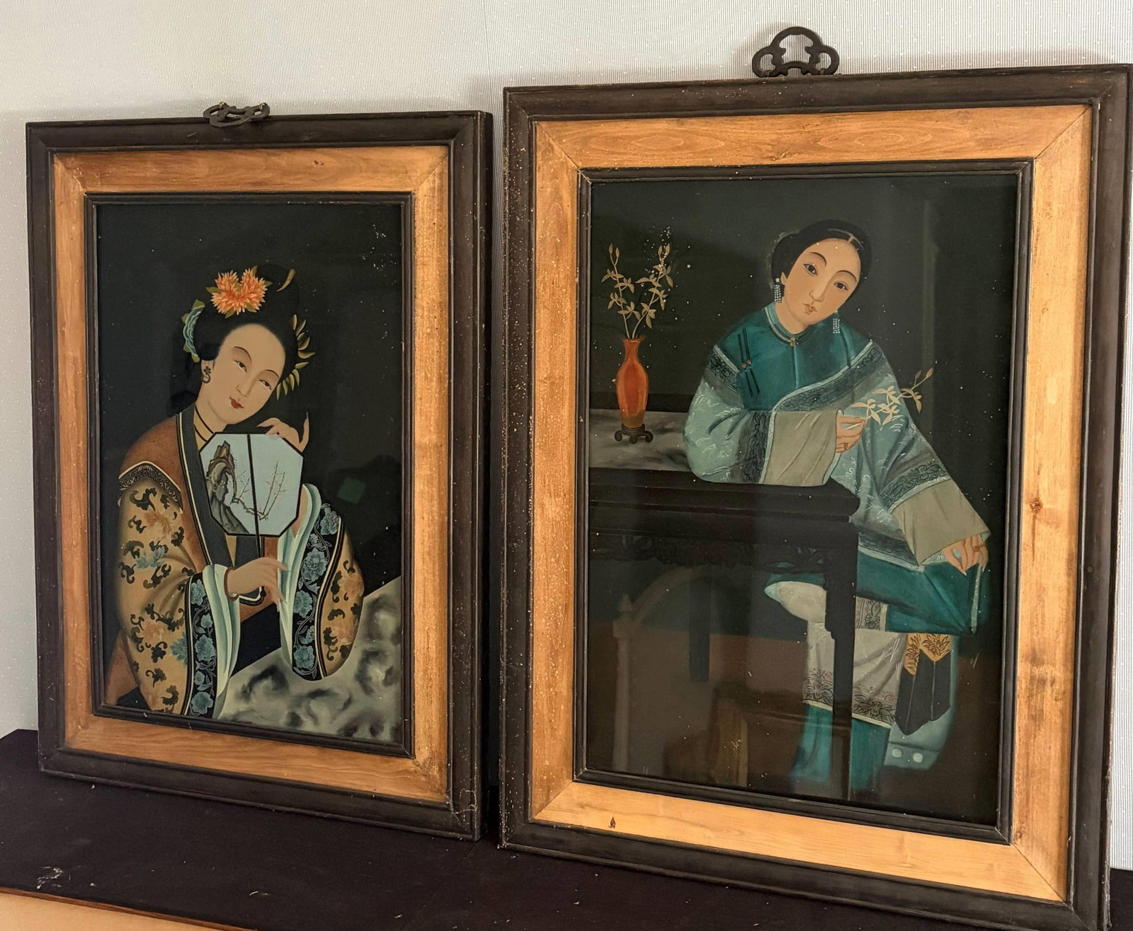 PAIR OF CHINESE REVERSE PAINTINGS ON GLASS DEPICTING COURT BEAUTIES - 26 1/2 in. x 20 in.; frame, 30: PAIR OF CHINESE REVERSE PAINTINGS ON GLASS DEPICTING COURT BEAUTIES One figure holds fan, the other seated at writing table beside coral-red vase; ebonized and gilt frames with brass hanging hardware 