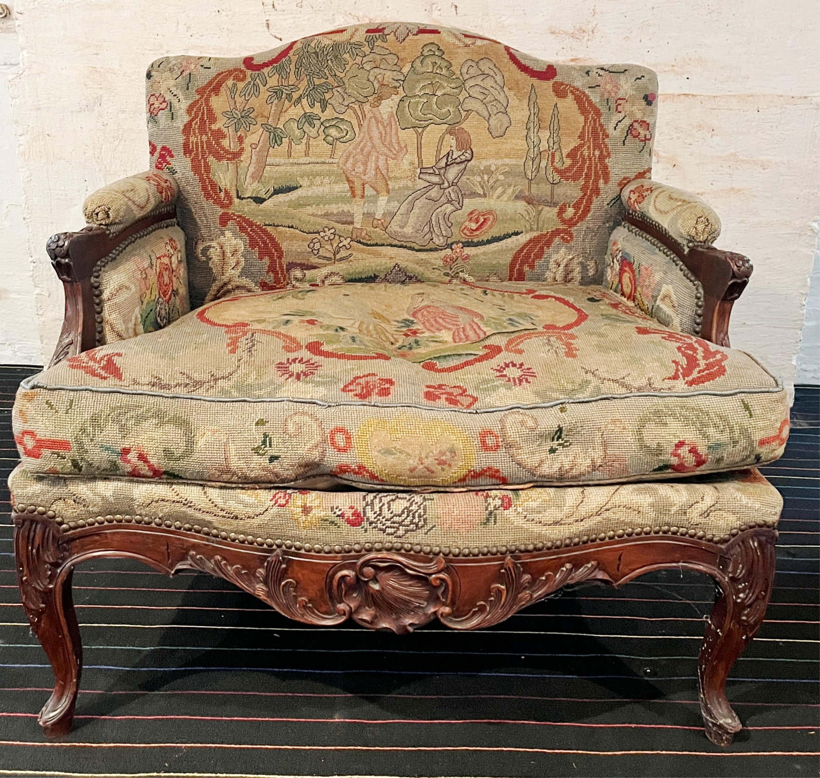 LOUIS XV STYLE TAPESTRY-UPHOLSTERED MARQUISE - H: 35 IN; W: 36 IN; D: 29 IN.: LOUIS XV STYLE TAPESTRY-UPHOLSTERED MARQUISE Carved frame; antique gros-point and petit-point upholstery depicting figures in landscape and parrots H: 35 IN; W: 36 IN; D: 29 IN PROVENANCE: ?Merry Hill