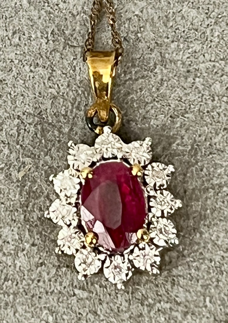 10K YELLOW GOLD, DIAMOND AND RUBY OVAL PENDANT ON CHAIN Oval ruby weighing approximately .75 ct.: 10K YELLOW GOLD, DIAMOND AND RUBY OVAL PENDANT ON CHAIN Oval ruby weighing approximately .75 ct. Surrounded by 12 matched round diamonds. Pendant, L: 3/4".