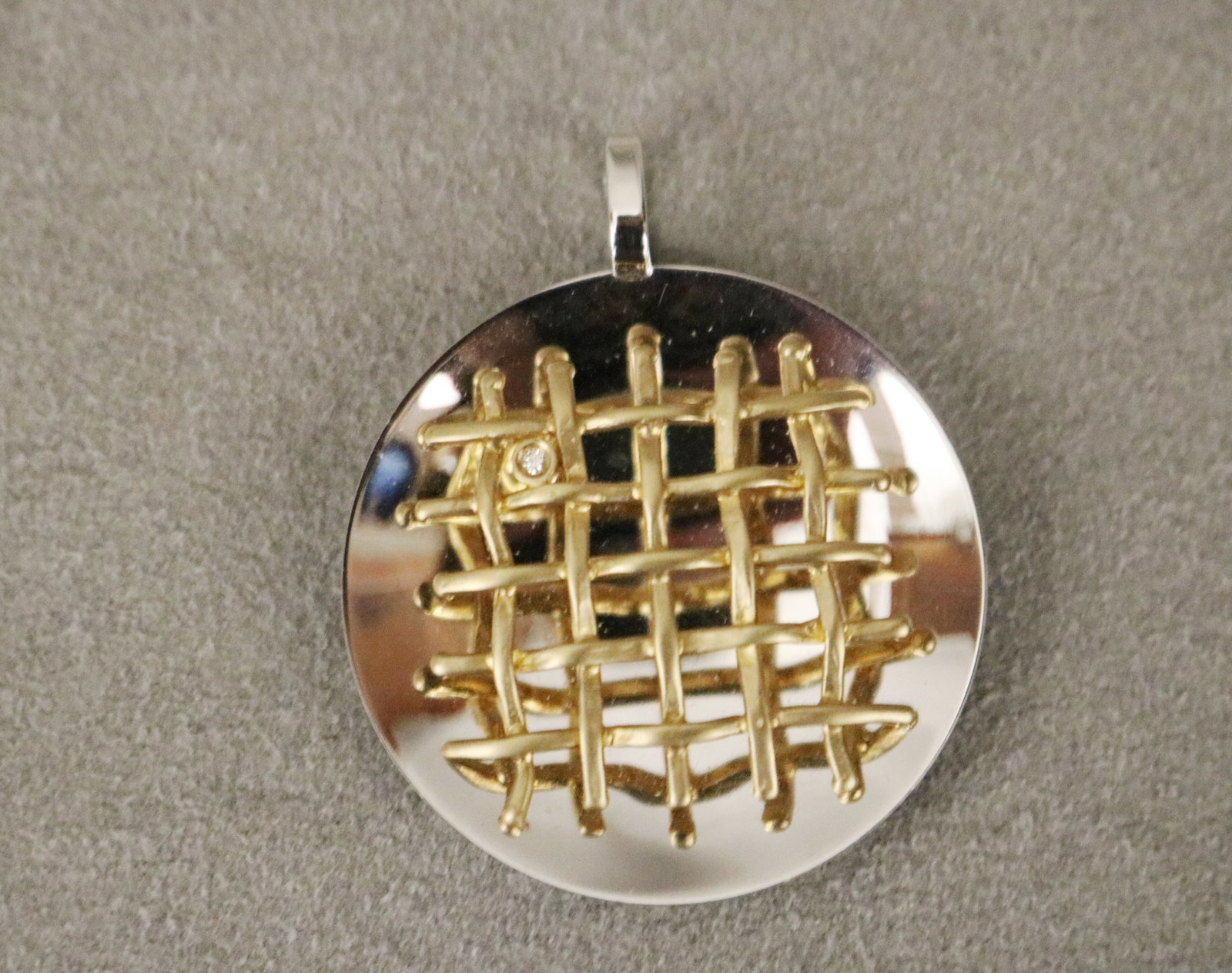 ITALIAN 14K WHITE AND YELLOW GOLD AND DIAMOND CONTEMPORARY DESIGN CIRCULAR PENDANT Bright-polished: ITALIAN 14K WHITE AND YELLOW GOLD AND DIAMOND CONTEMPORARY DESIGN CIRCULAR PENDANT Bright-polished saucer shape white gold pendant with yellow gold grid off-set with one round diamond D: 1 1/4 in. Wt.
