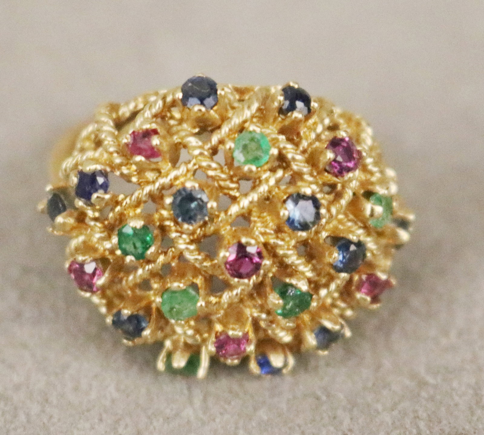 14K YELLOW GOLD AND COLORED GEMSTONE OPENWORK, ROPE-DESIGN BASKETWEAVE DOME RING 23 matched round: 14K YELLOW GOLD AND COLORED GEMSTONE OPENWORK, ROPE-DESIGN BASKETWEAVE DOME RING 23 matched round sapphires, rubies and emeralds Ring size: 9. Gross wt. 6 dwt