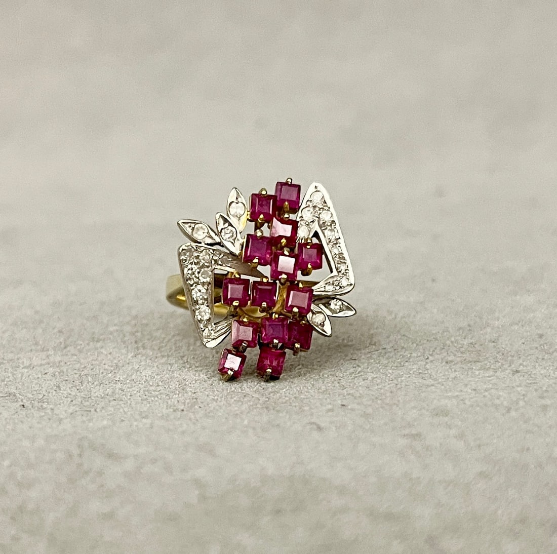 14K YELLOW AND WHITE GOLD, DIAMOND AND RUBY GEOMETRIC DESIGN RING Vertically-oriented, domed: 14K YELLOW AND WHITE GOLD, DIAMOND AND RUBY GEOMETRIC DESIGN RING Vertically-oriented, domed arrangement of 14 square-cut rubies, centered by 22 round diamonds in openwork setting. Ring size: 6 1/2". 
