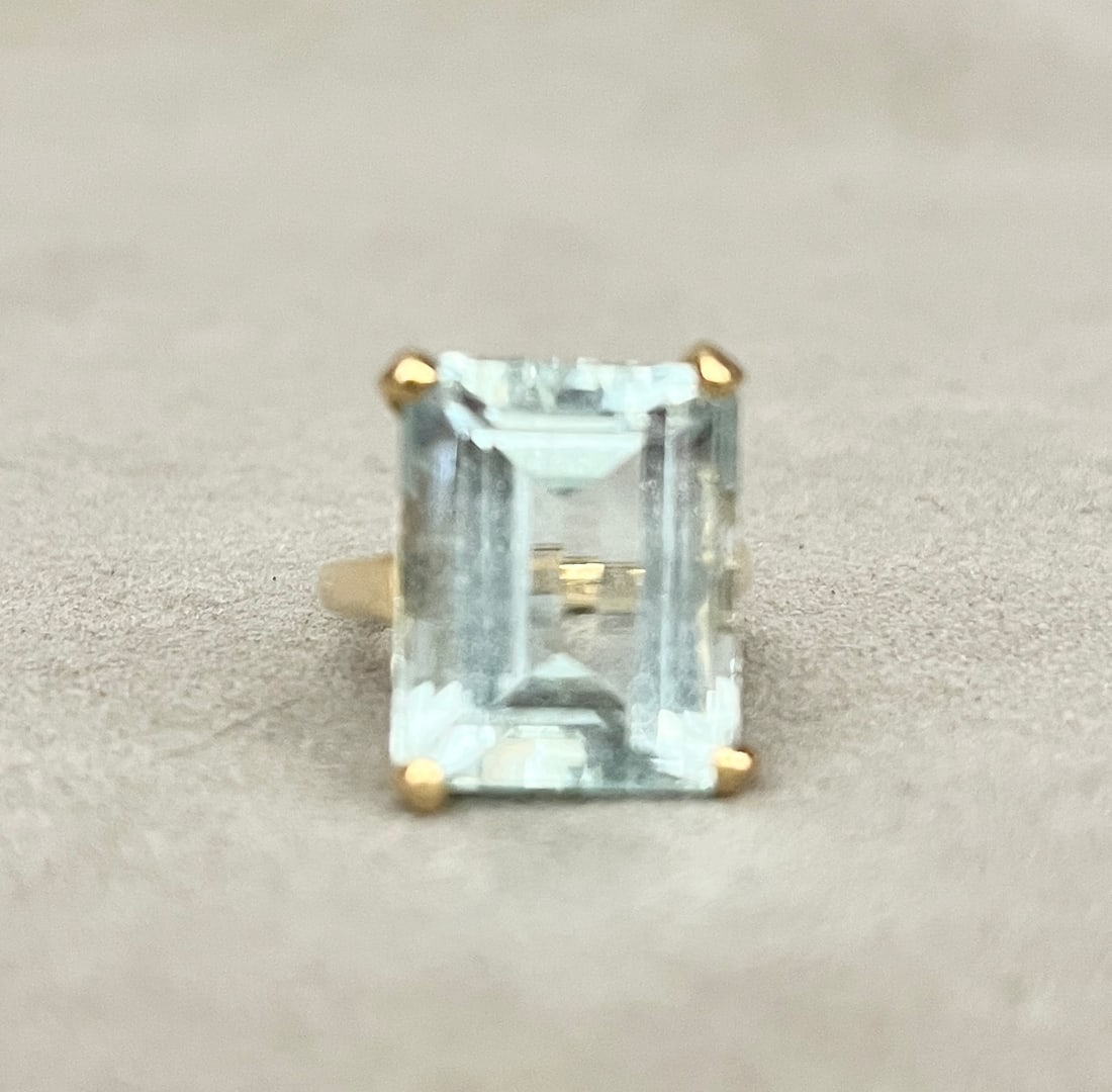 18K YELLOW GOLD AND AQUAMARINE RING Emerald-cut aquamarine held by four corner prongs in weighing: 18K YELLOW GOLD AND AQUAMARINE RING Emerald-cut aquamarine held by four corner prongs in weighing approximately 8-10 ct. setting with pierced sides. Ring size: 7. Gross wt: 6 dwt.