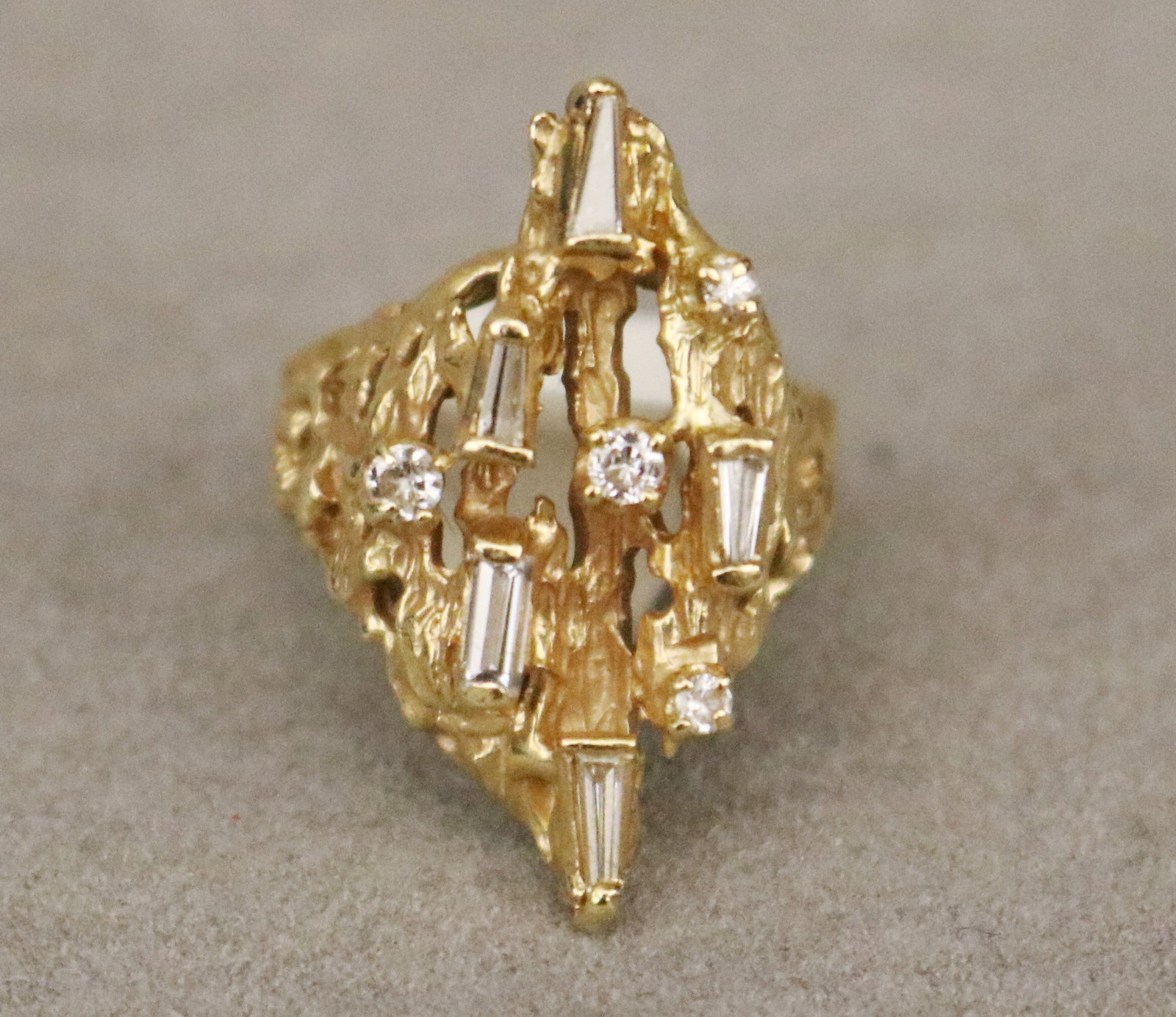 18K BARK-TEXTURED YELLOW GOLD AND DIAMOND OPENWORK CONTEMPORARY DESIGN RING Top section set with: 18K BARK-TEXTURED YELLOW GOLD AND DIAMOND OPENWORK CONTEMPORARY DESIGN RING Top section set with four graduated brilliant-cut round diamonds and five tapering and straight diaomond baguettes. Ring siz