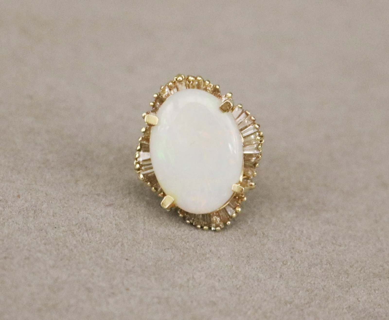 14K YELLOW GOLD, DIAMOND AND PRECIOUS WHITE OPAL RING Flat oval opal panel raised by four prongs: 14K YELLOW GOLD, DIAMOND AND PRECIOUS WHITE OPAL RING Flat oval opal panel raised by four prongs in ballerina setting with four round and 30 baguette diamonds together weighing app. 1.50 ct. Ring size