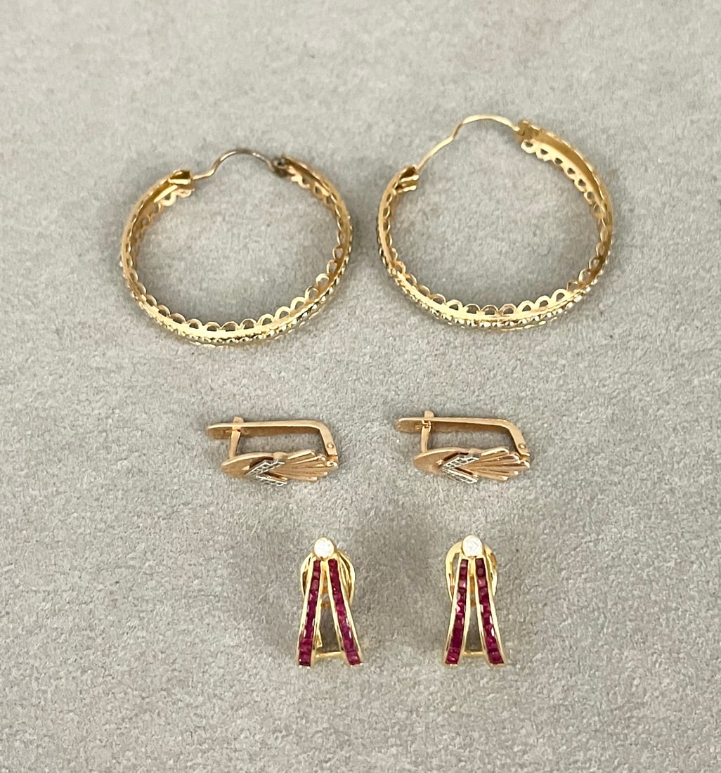 THREE PAIRS YELLOW GOLD EARRINGS Including pair 18K yellow and white gold openwork hoops, D: 1: THREE PAIRS YELLOW GOLD EARRINGS Including pair 18K yellow and white gold openwork hoops, D: 1 3/8"; pair 18K yellow gold inverted V- form with two channels of calibre-cut square rubies surmounted by 