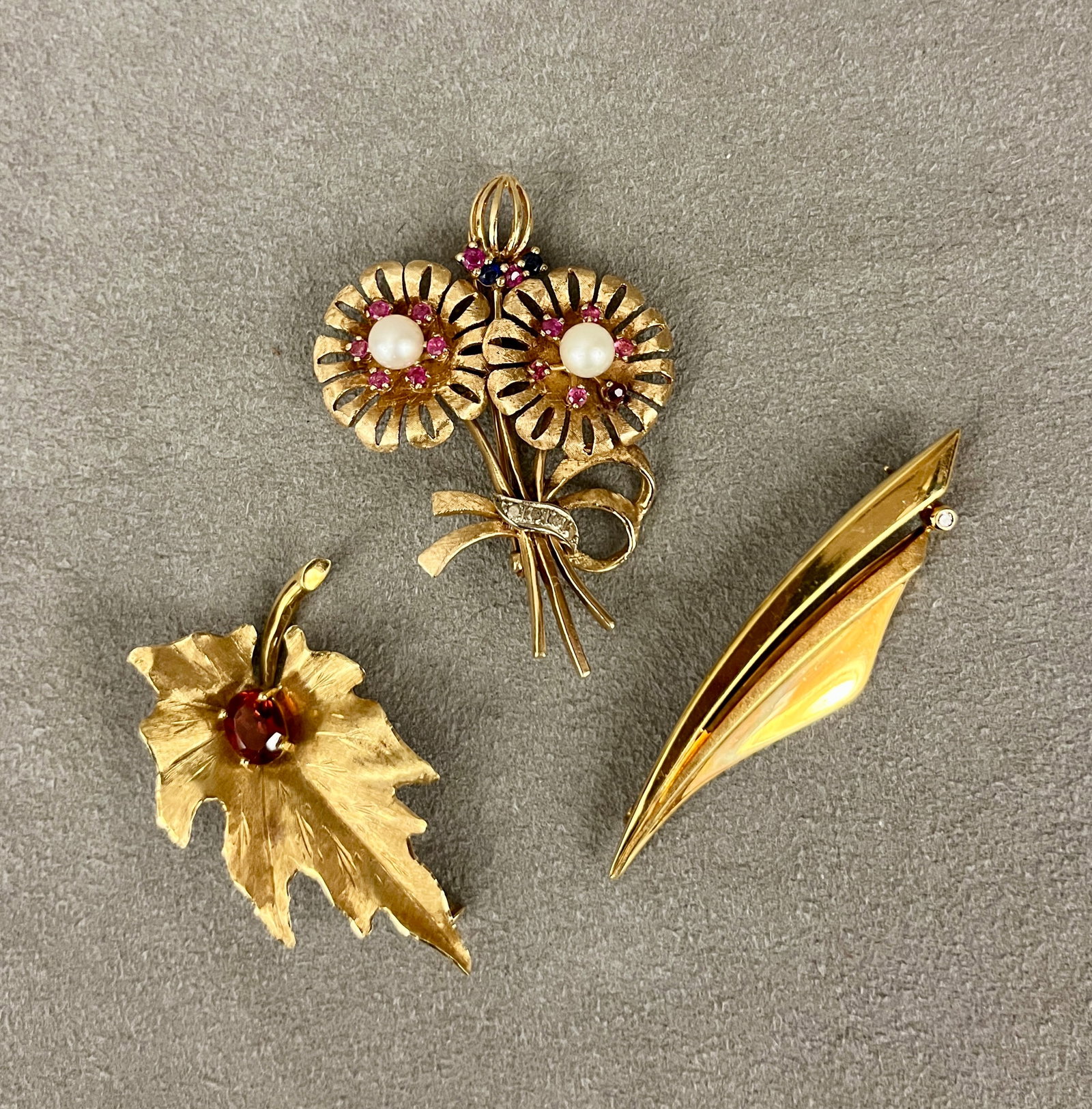 THREE ASSORTED YELLOW GOLD PINS WITH GEMSTONE ACCENTS One, 18K leaf design set with oval: THREE ASSORTED YELLOW GOLD PINS WITH GEMSTONE ACCENTS One, 18K leaf design set with oval orange-red garnet, gross wt: 4 dwt; 14K twin-flower design set with two 5.5 mm cultured pearls, 14 pink rubies 